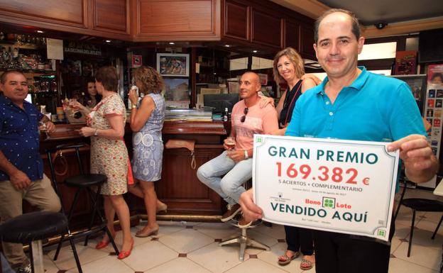 El titular de la Administración de Lotería posa con el número premiado.