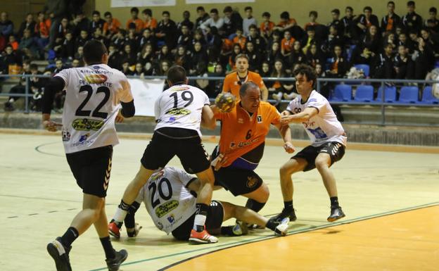 El pivote Sebas se dispone a la lanzar agarrado por varios rivales del Gijon. /MANUEL LAYA