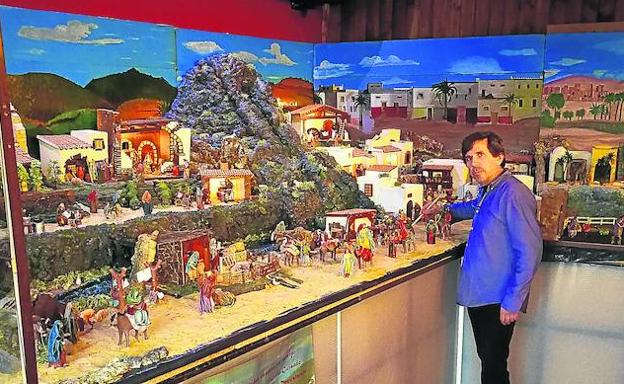 Juan Carlos Sánchez junto al gran belén tradicional que ha montado en su bar-restaurante de Escurial de la Sierra, que tiene unas dimensiones de dos metros de ancho por ocho de largo./M. J. G.