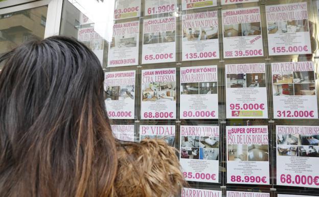 Una joven observa los anuncios de viviendas en el escaparate de una inmobiliaria. /MANUEL LAYA