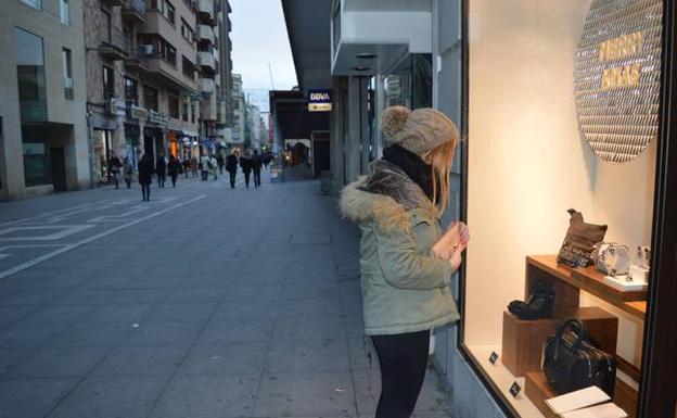 Una joven mira el escaparate de un comercio en la calle Santa Clara./A. P.