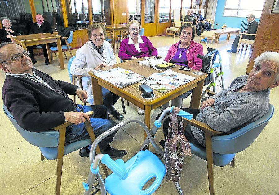 Un grupo de personas mayores de la residencia pasan el rato leyendo y conversando.