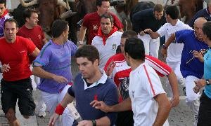 Alexander Fiske-Harrison, en primer plano, con el 'Financial Times' en la mano, corre delante de los toros, la semana pasada en Cuéllar. / A. TANARRO/