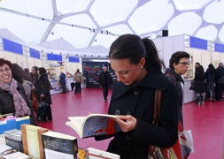 Una mujer ojea un libro durante la pasada edición de la Feria del Libro de Valladolid, realizada también en la Cúpula del Milenio / R. Gómez/