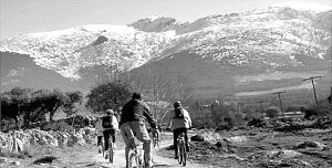 Unos ciclistas pasean a los pies de la sierra y con el pico de la Mujer Muerta al fondo. / I. JIMENO/