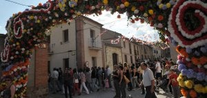 El cortejo de vecinos durante la recogida de las santeras pasa por uno de los arcos de flores bajo los que pasará la Virgen del Castillo en sus traslados. :: JAVIER SEGOVIA / GALERÍA DE FOTOS EN NORTECASTILLA.ES/