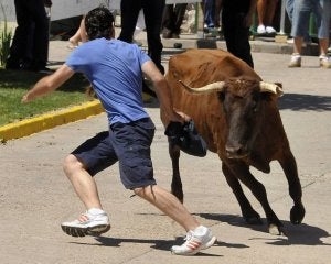 Un joven esquiva a un toro en el encierro matinal. :: FRAN JIMÉNEZ/