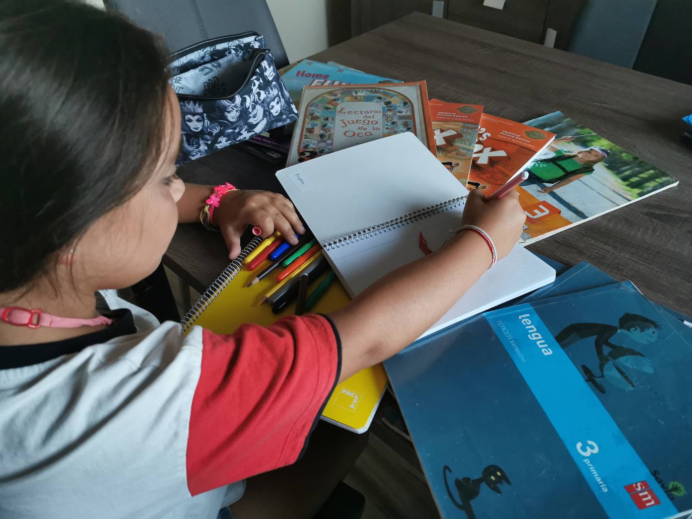 Una niña revisa sus libros y material escolar para el próximo curso /LAURA NEGRO