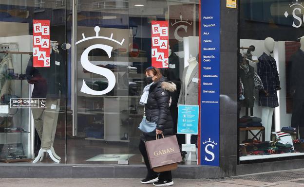 Una mujer pasa delante de un escaparate con cartelería de rebajas.
